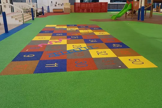 Colorful playground with rainbow painted on floor, inviting children to play and have fun outdoors.