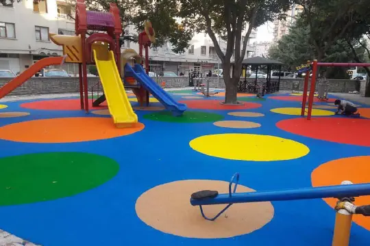 Play area with colorful equipment and rainbow pattern on floor, perfect for kids to enjoy and explore.