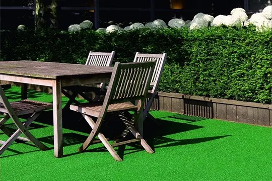 Outdoor dining set with table and chairs on lush green grass.